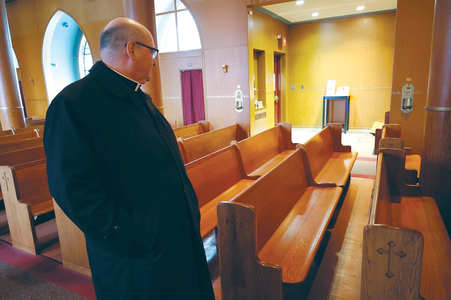 During a visit to Holy Name of Mary Church, Bishop Henning pauses at a pew where his grandparents once sat each week as they participated in Sunday Mass.